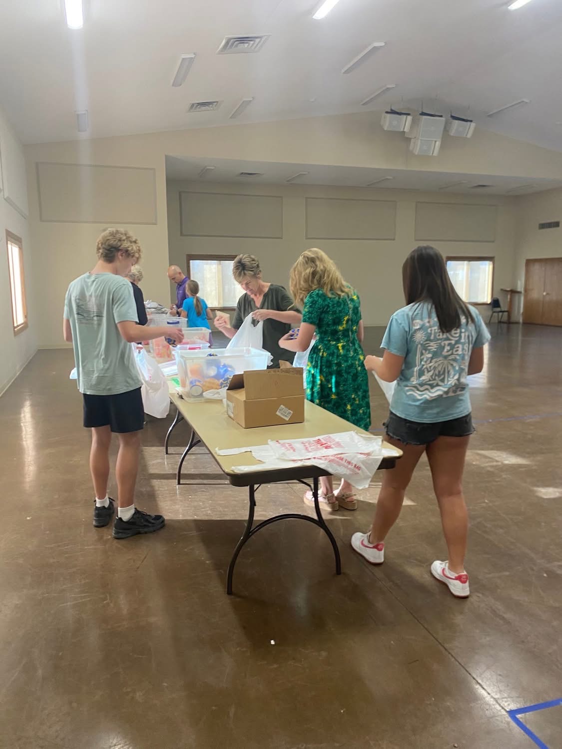 Volunteers filling weekend care pack bags together at a table