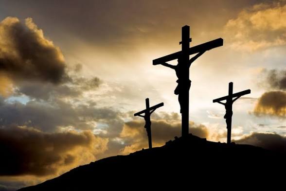 Three crosses silhouetted against a golden sunset sky